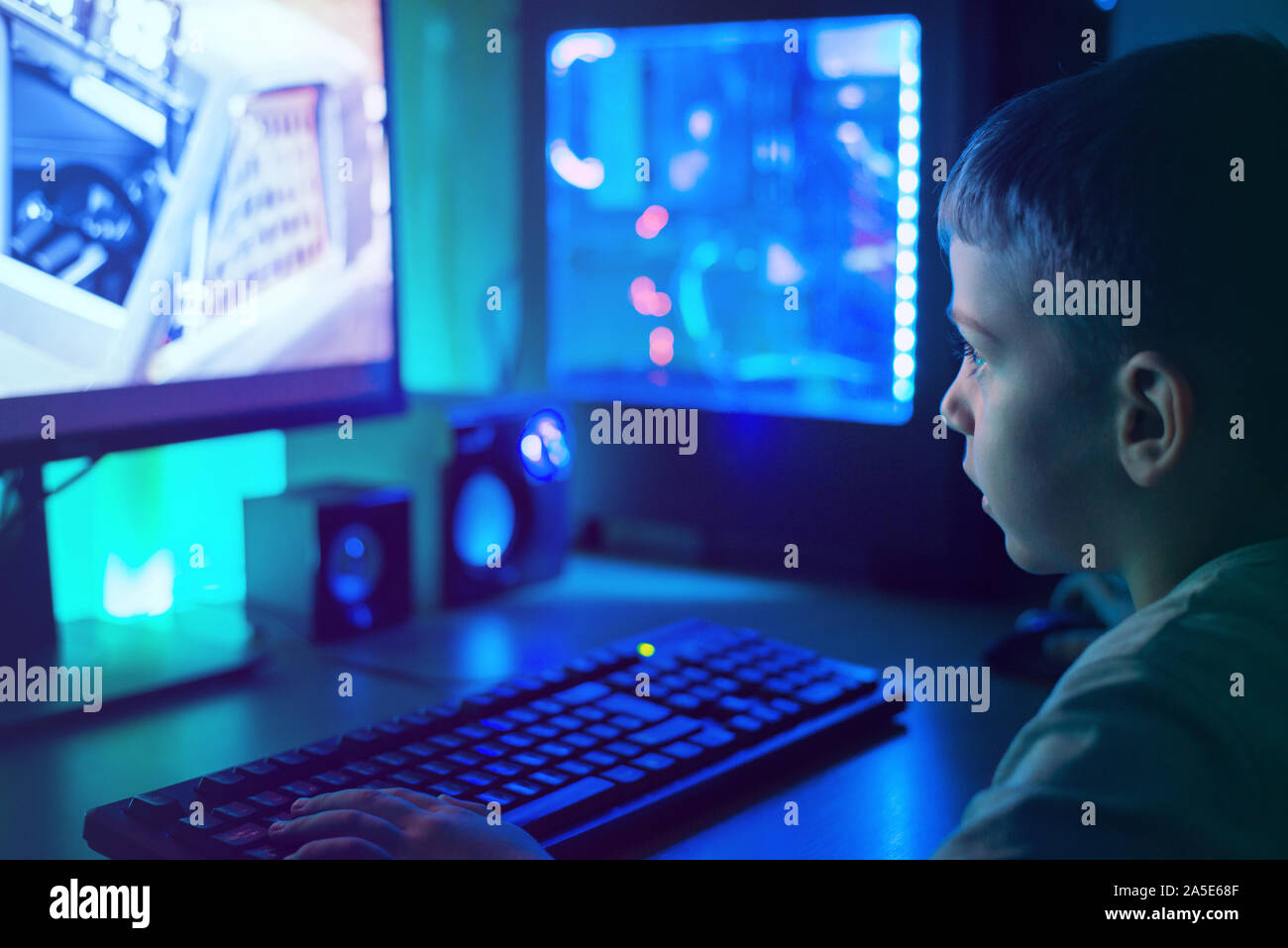 Jungen spielen auf modernen PC mit RGB-Leuchten. Dunkle Szene, close-up. Stockfoto