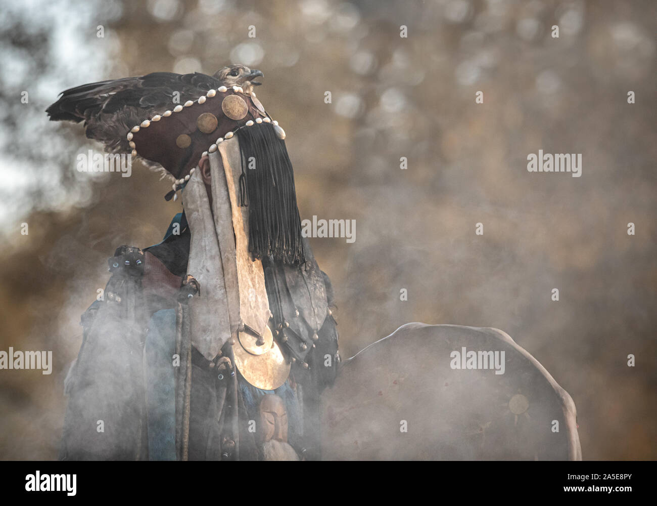 Traditioneller Mongolischer Schamane Durchführen einer traditionellen schamanistisches Ritual mit einer Trommel und Rauch in einem Wald im Herbst am Nachmittag. Ulaanbaatar, Mongo Stockfoto