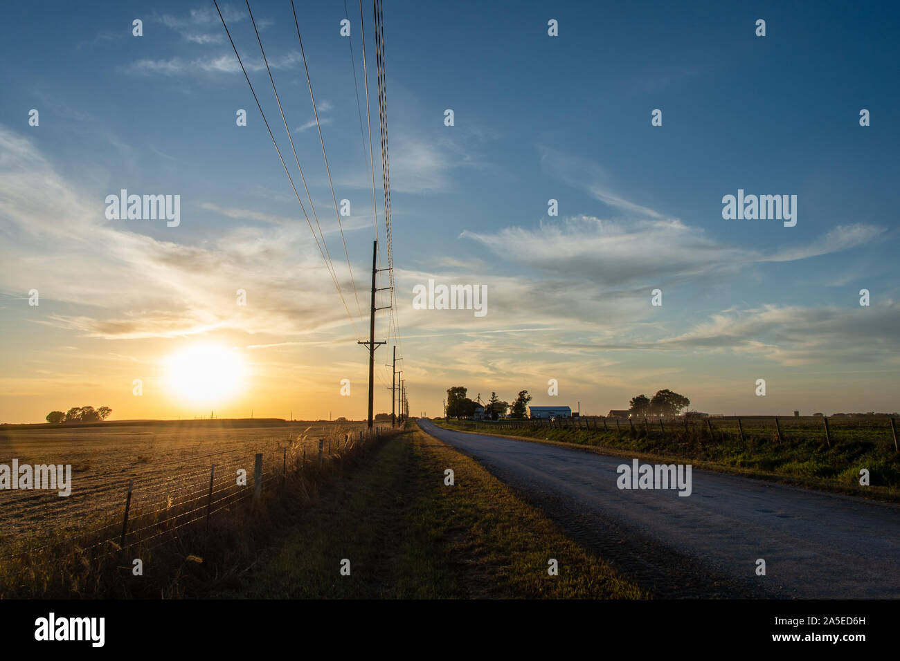 Sonnenuntergang highlights Ackerland, Versorgungsleitungen und landwirtschaftlichen Gebäuden in der Nähe des Hohen Trestle Trail in der Polk County, Iowa. Stockfoto