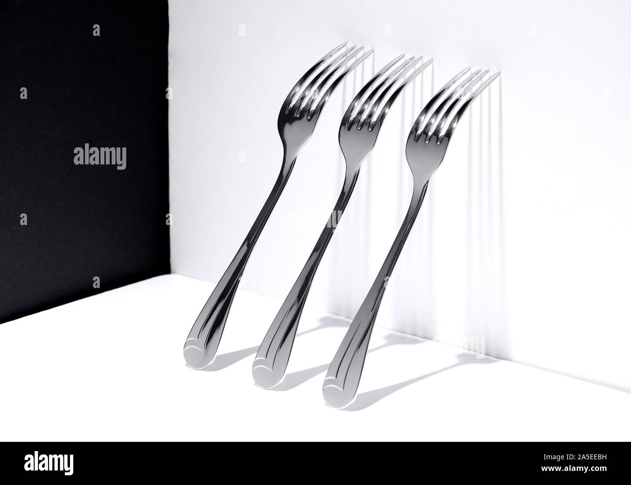 Drei Gabeln auf einer weißen Wand mit der Schattenwurf auf dieser ruhenden, konzeptionelle Foto Stockfoto