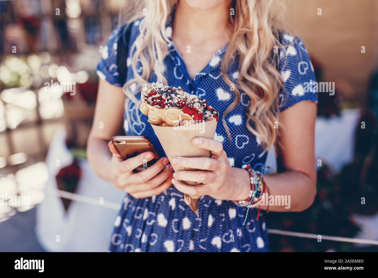Junge blonde Frau mit Bubble Waffel bei Strawberry Festival Stockfoto