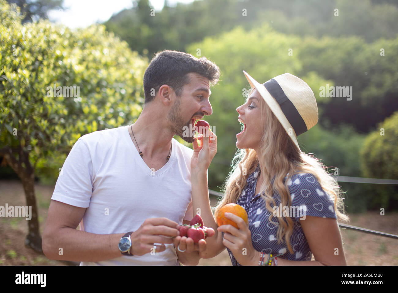 Junge Frau Fütterung Freund mit Erdbeeren in der Natur auf Picknick Stockfoto