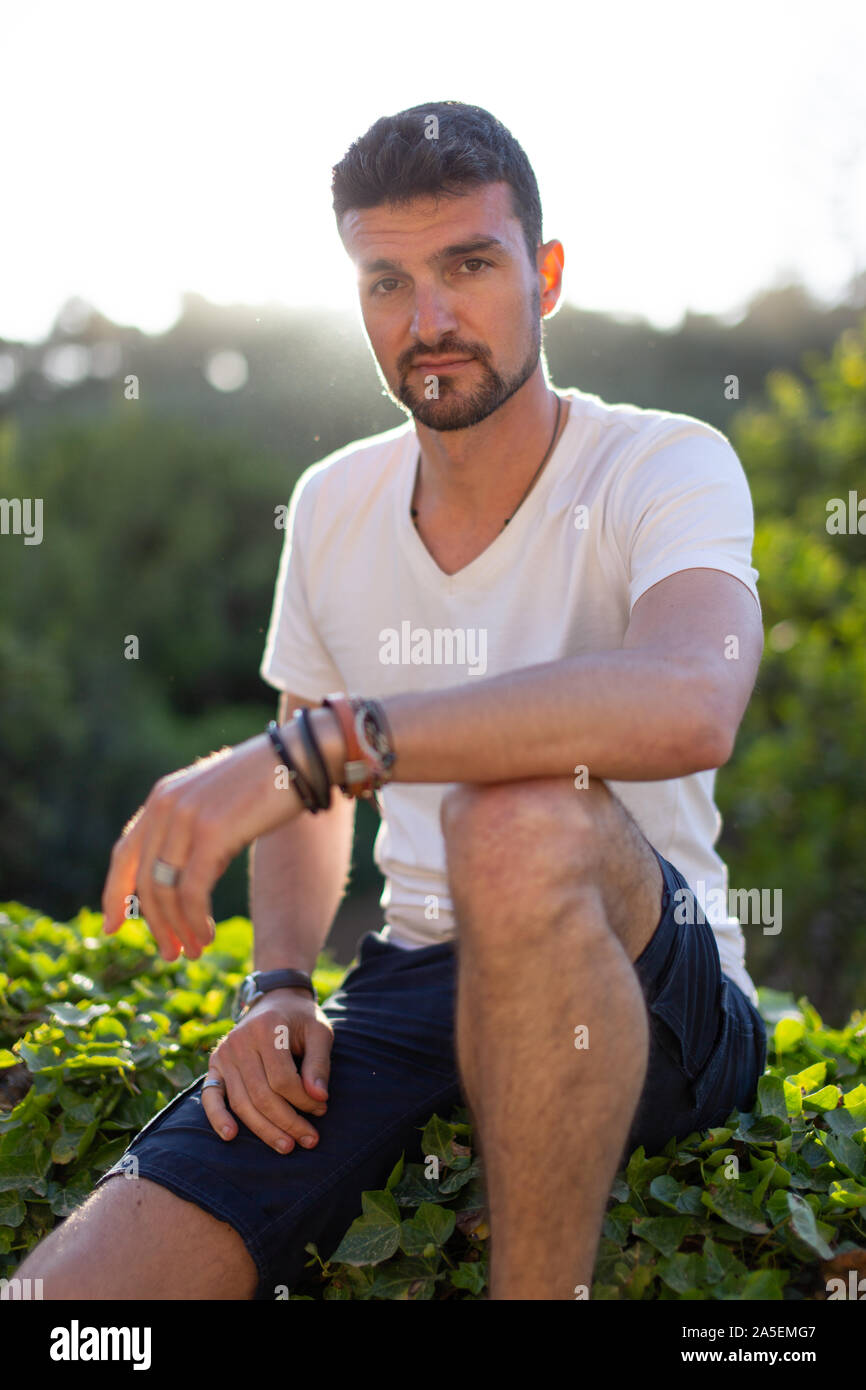 Junge 20 s Casual kaukasischen Mann in der Natur sitzen Stockfoto