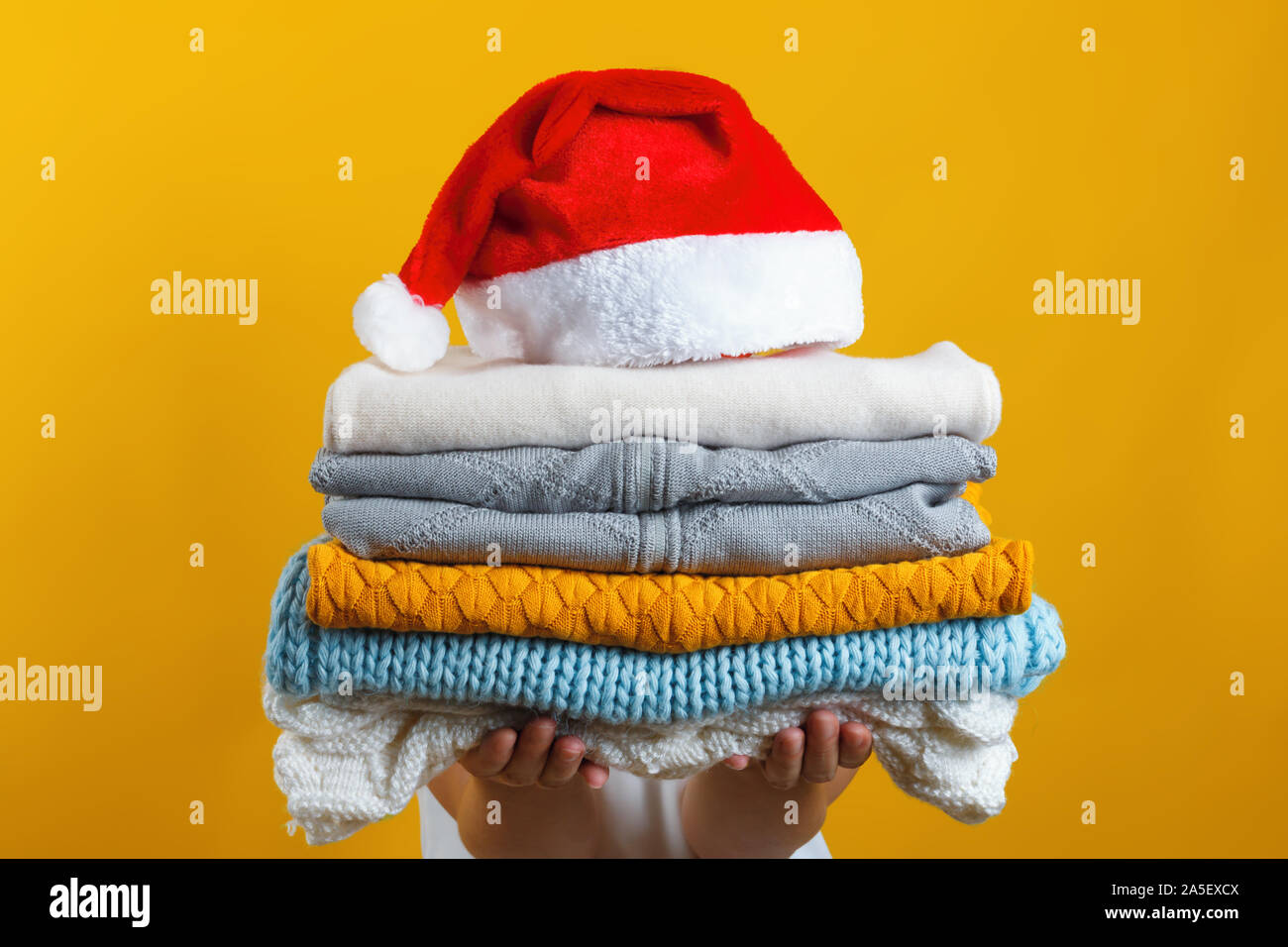 Eine Frau hält einen Stapel von warmen gestrickten Kleider, Santa Hut oben ist. Winter und Weihnachten Konzept. Stockfoto