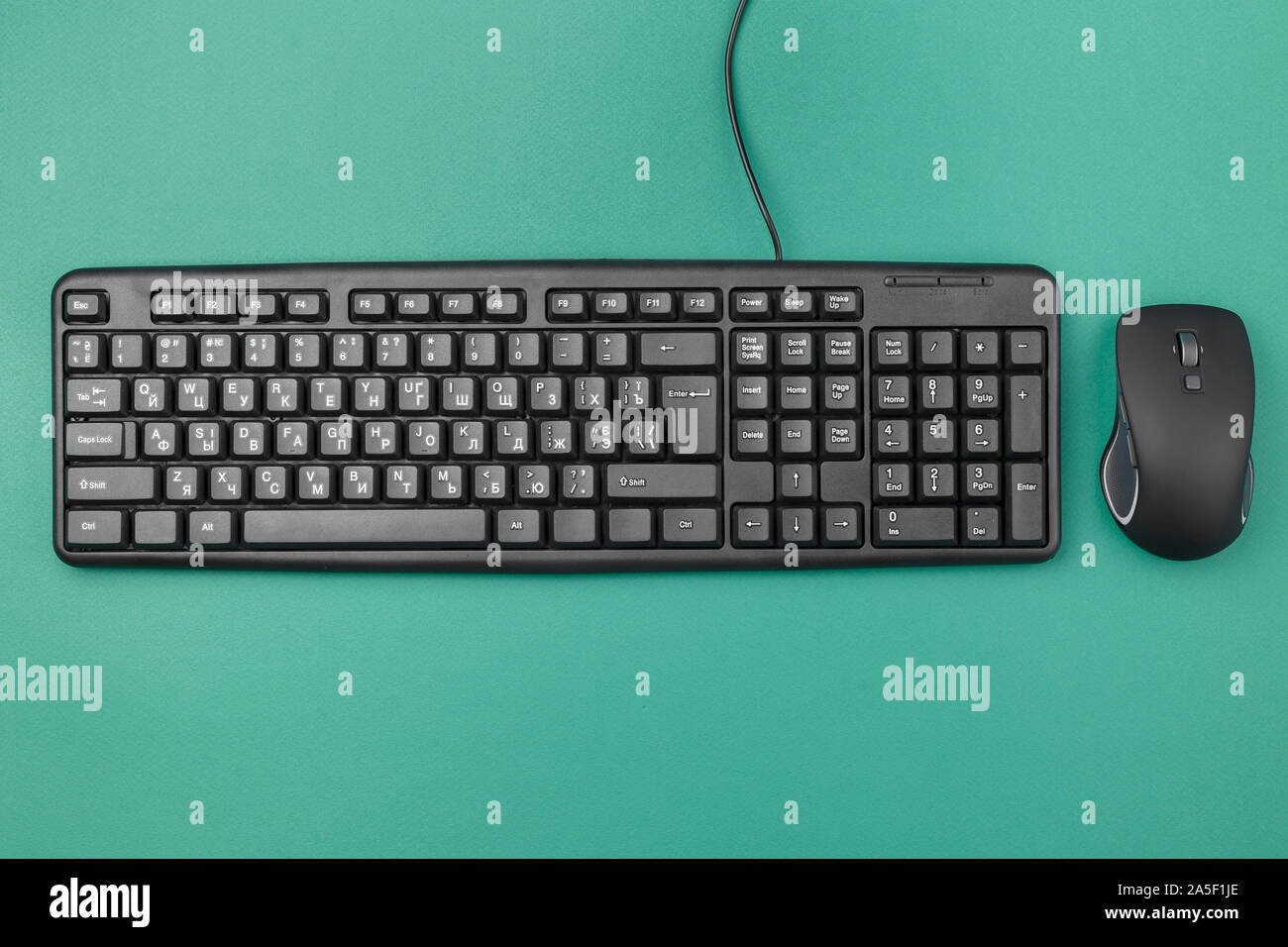 Tastatur für Computer mit einem Kabel auf dem Tisch. In der Nähe liegt eine kabellose Maus. Moderne Bürogeräte Stockfoto