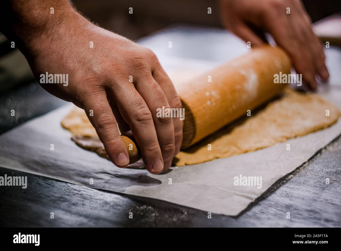 Bäcker Händen rollen Ingwer Teig auf einem dunklen Hintergrund. Nahaufnahme, Soft Focus. Seitenansicht, Draufsicht. Kopieren Sie Platz. Stockfoto