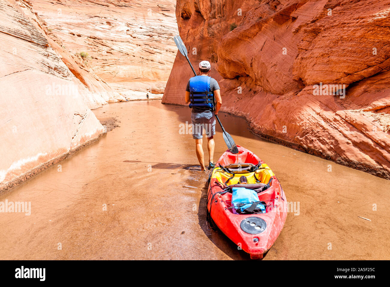 Kajak Trail im Lake Powell Antelope Canyon mit schmalen Mann holding Paddel Ruder ziehen Kajak Boot zu tieferen schmutzige schlammige Wasser Stockfoto