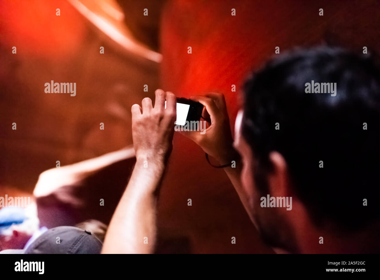 Seite, USA - 10. August 2019: Reisegruppe und Nahaufnahme zurück junger Mann innerhalb Upper Antelope Slot Canyon in Arizona Aufnehmen von Bildern mit der Kamera Stockfoto