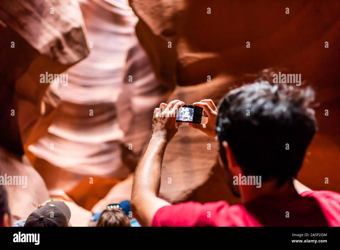 Seite, USA - 10. August 2019: Tour Gruppe junger Mann zurück in Upper Antelope Slot Canyon in Arizona Aufnehmen von Bildern mit der Kamera aus Sandstein Format Stockfoto