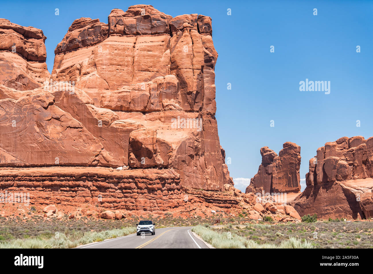 Moab, USA - 13. August 2019: Auto auf Utah Scenic Byway Highway 191 Straße mit hohen hohen Butte mesa Canyon Klippen in der Nähe von Canyonlands Stockfoto