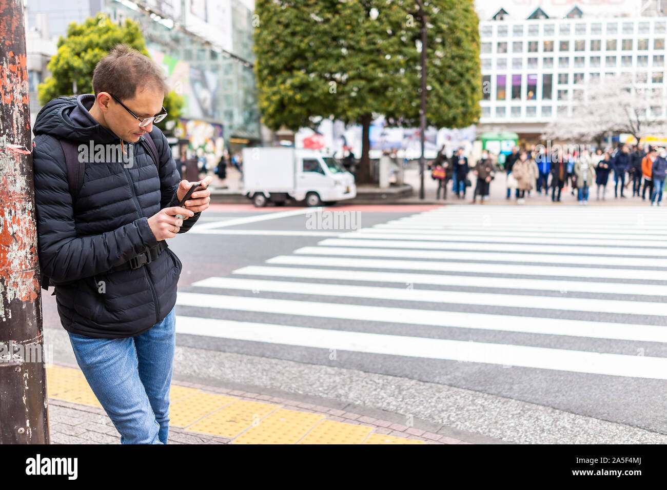 Tokio, Japan berühmten Shibuya Crossing crosswalk in Downtown City mit man touristische stehend an Richtungen auf Telefon Stockfoto