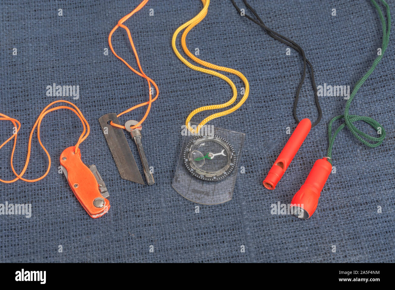 Überlebensfähigkeiten und Ausrüstung. High vis Überleben Feuerzeug, Überlebenspfeife, High viz Überleben Taschenlampe, High viz Messer, Überlebenskompass, Notfall-Kit. Stockfoto