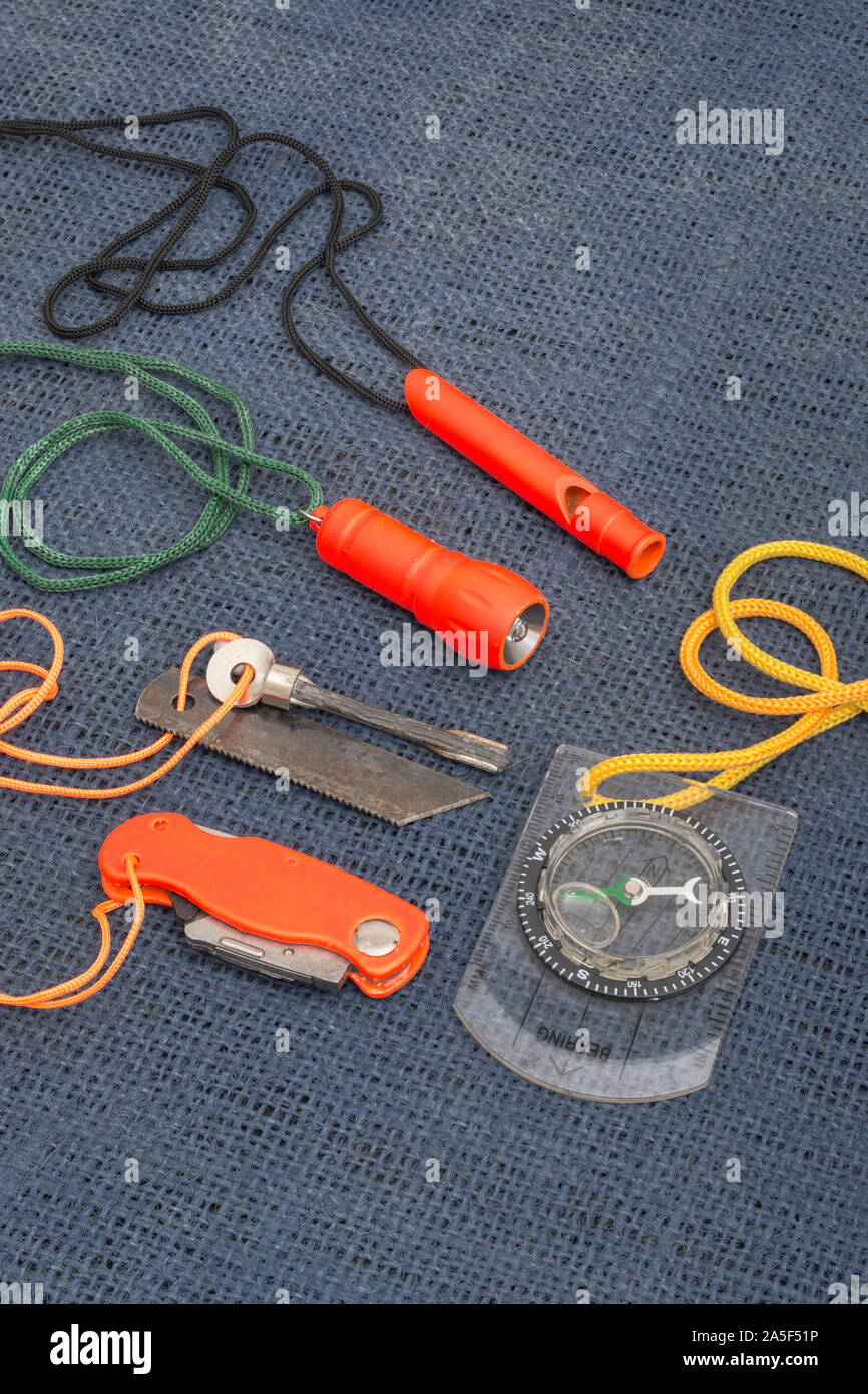 Überlebensfähigkeiten und Ausrüstung. High vis Überleben Feuerzeug, Überlebenspfeife, High viz Überleben Taschenlampe, High viz Messer, Überlebenskompass, Notfall-Kit. Stockfoto