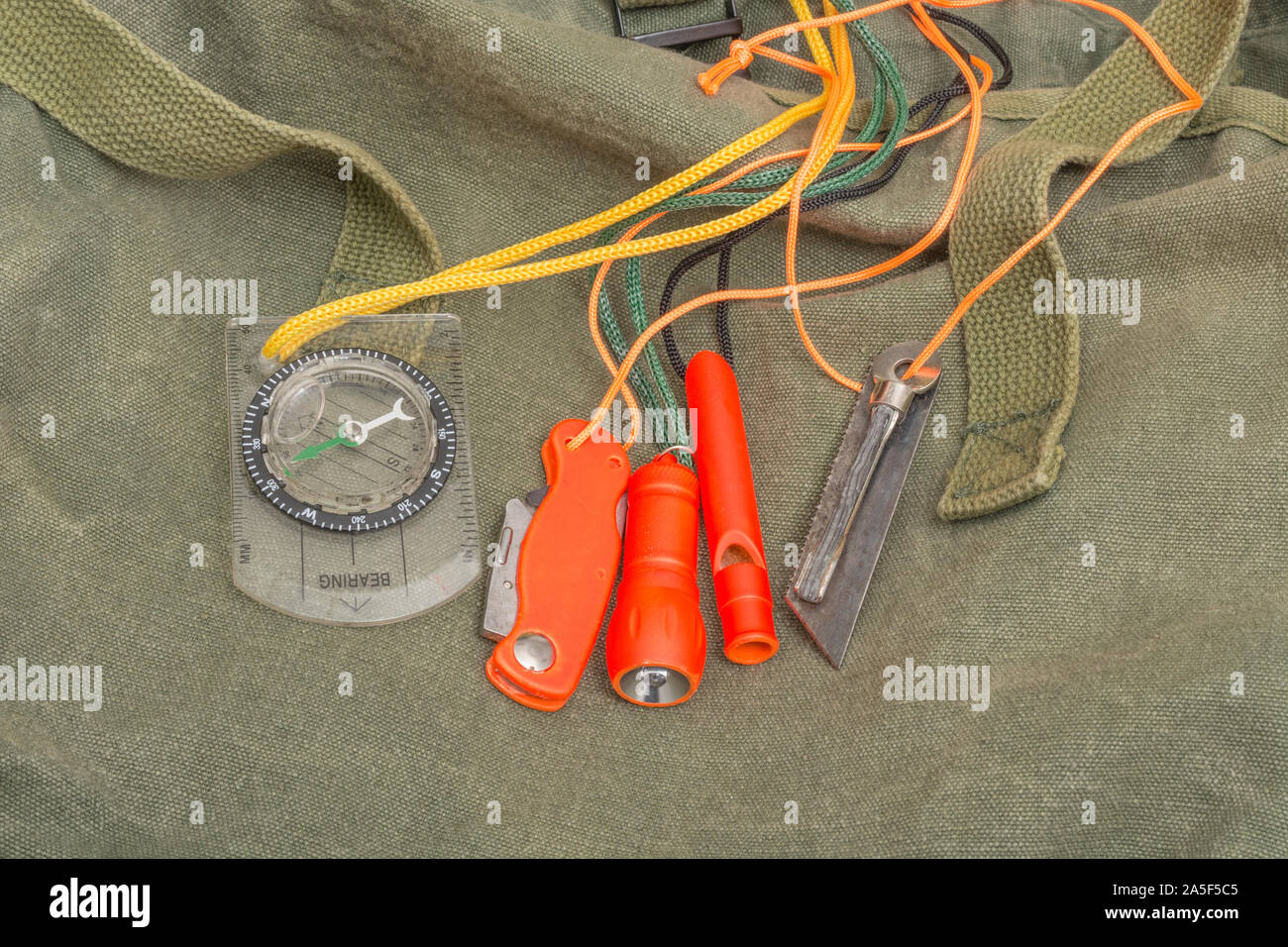 Überlebensfähigkeiten und Ausrüstung. High vis Überleben Feuerzeug, Überlebenspfeife, High viz Überleben Taschenlampe, High viz Messer, Überlebenskompass, Notfall-Kit. Stockfoto