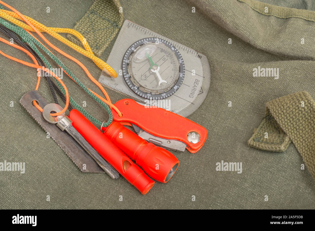 Überlebensfähigkeiten und Ausrüstung. High vis Überleben Feuerzeug, Überlebenspfeife, High viz Überleben Taschenlampe, High viz Messer, Überlebenskompass, Notfall-Kit. Stockfoto