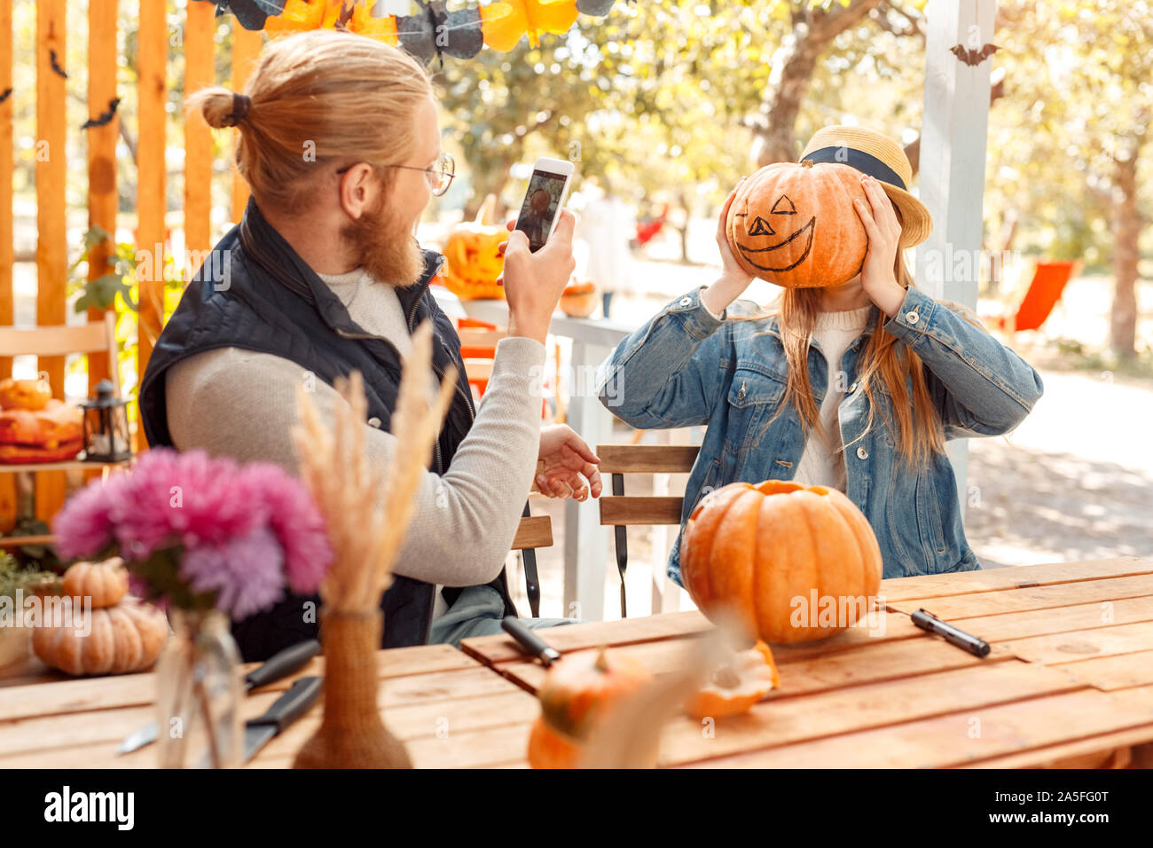 Halloween Einlieferung am Konzept. Junges Paar am Tisch im Freien, die Jack-o'-Lantern Mann unter Foto von Frau mit Kürbis sitzen Stockfoto