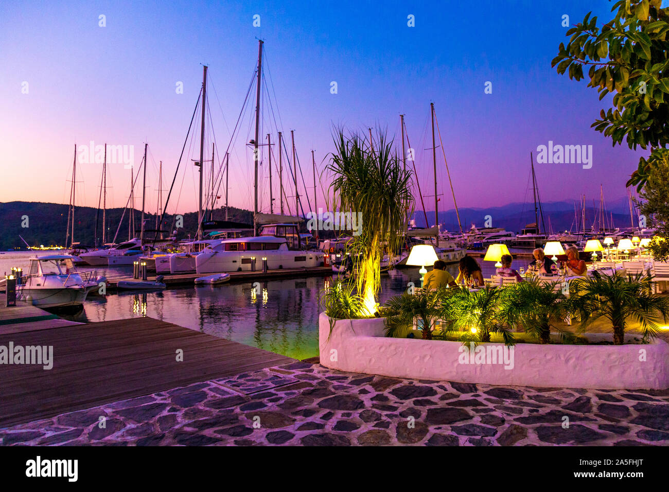 Die Menschen essen im Freien in der Dämmerung bei Mori Restaurant, Yacht Classic Hotel, Ece Marina Fethiye, Türkische Riviera, Türkei Stockfoto