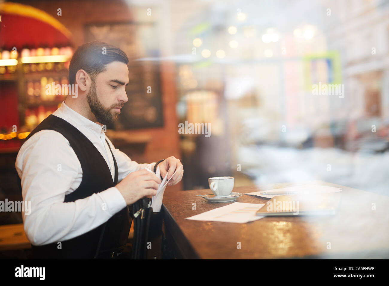 Seitenansicht Portrait von stattlichen Geschäftsmann im luxuriösen Restaurant arbeiten, geschossen von hinter Glas, Kopie Raum Stockfoto