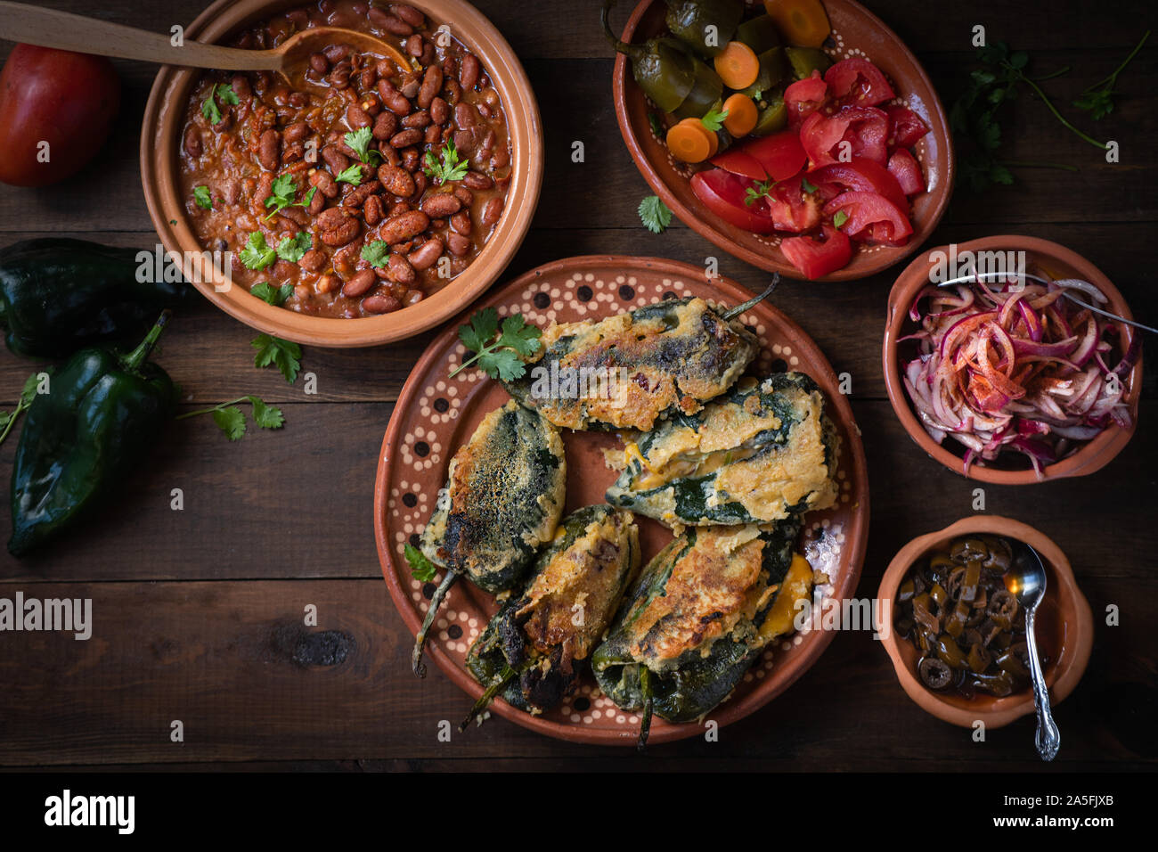 Chilles rellenos serviert in der traditionellen mexikanischen Gerichten, serviert mit Bohnen, Gurken Stockfoto