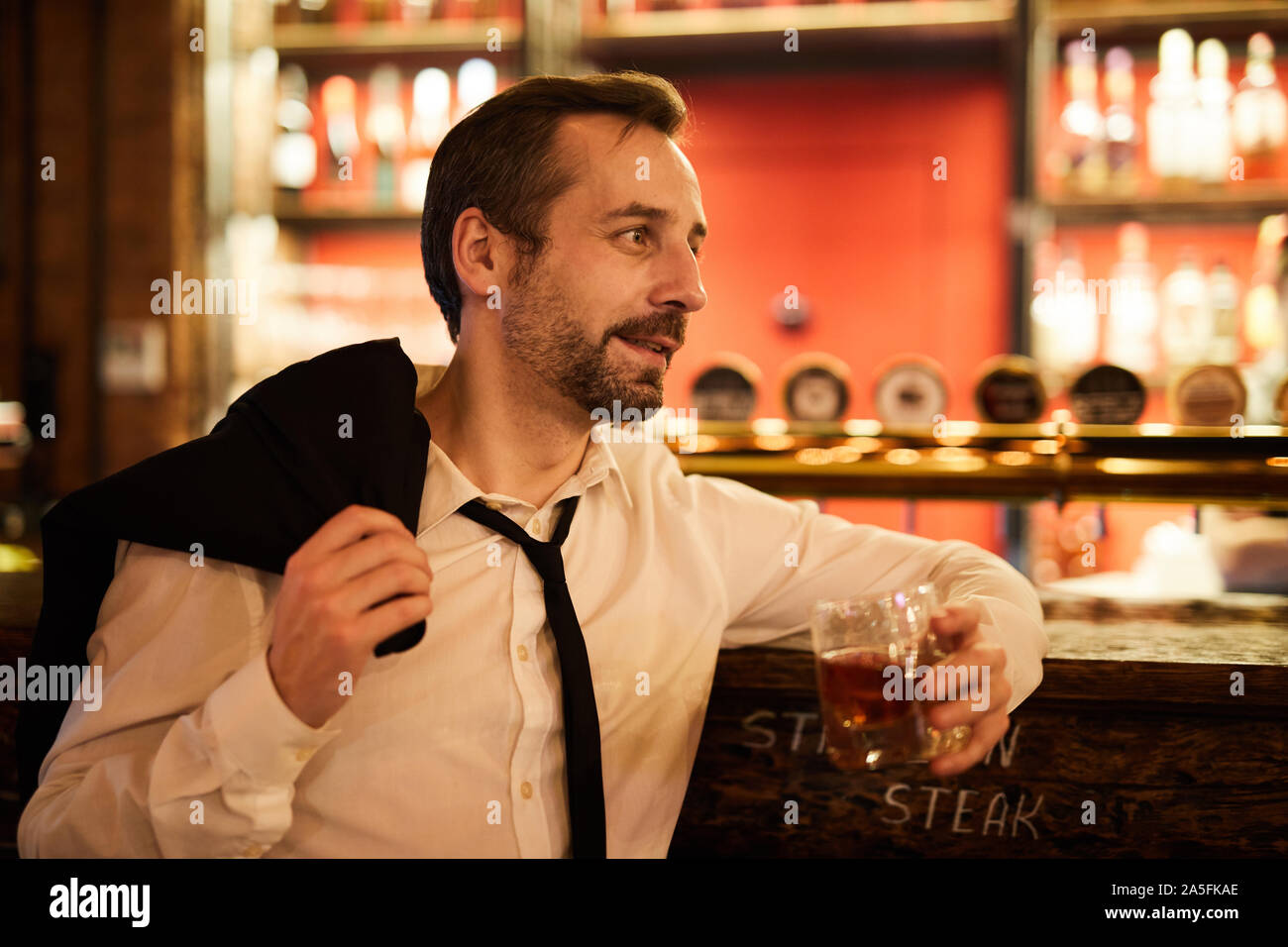Seitenansicht Portrait von bärtigen reife Geschäftsmann Whiskey trinken und entspannen Sie in der Bar nach der Arbeit Stockfoto
