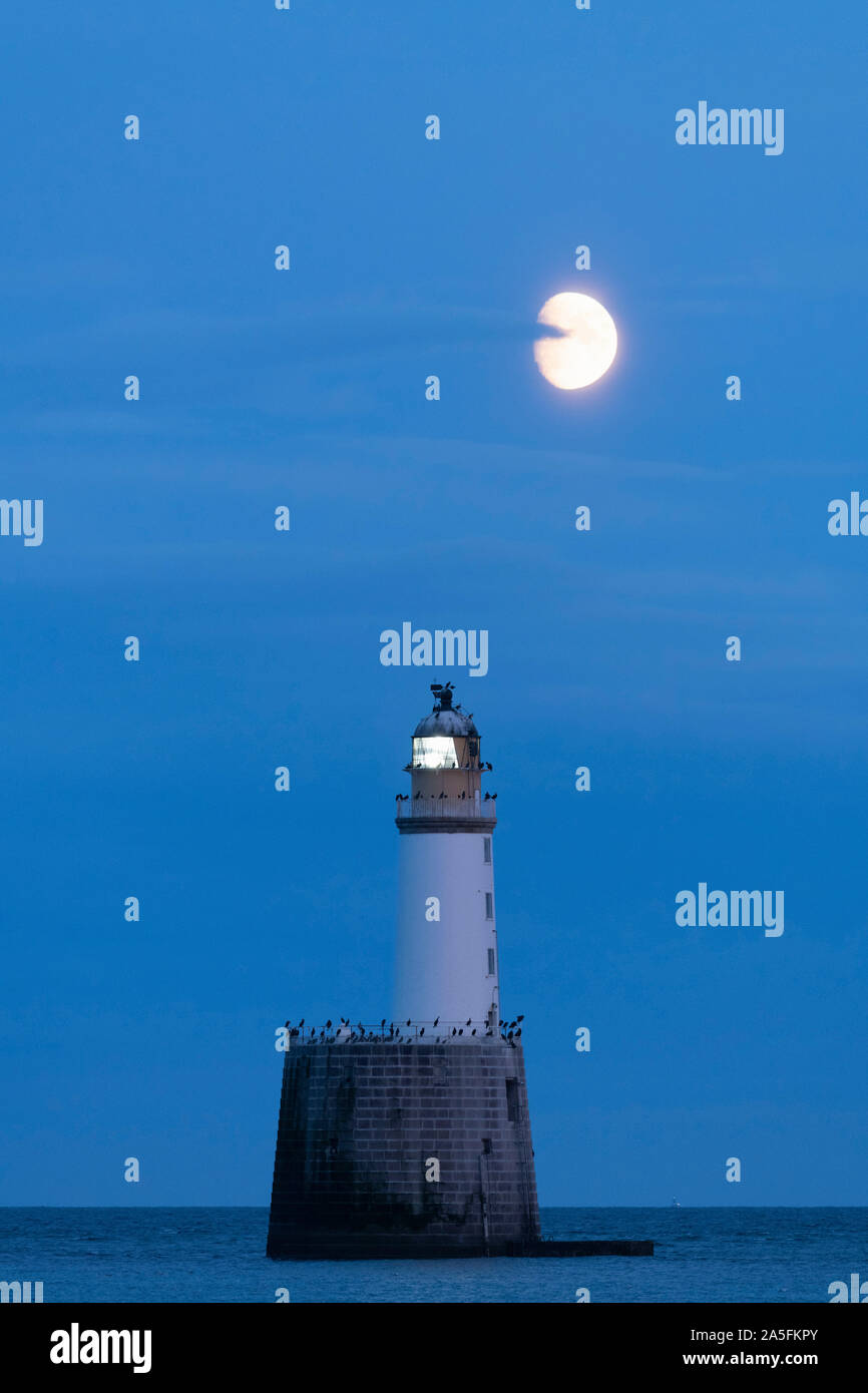 Rattray Head Lighthouse aus der nordöstlichen Küste von Schottland blinkt in der Dämmerung unter einem fast vollen Mond kurz nach Mondaufgang Stockfoto