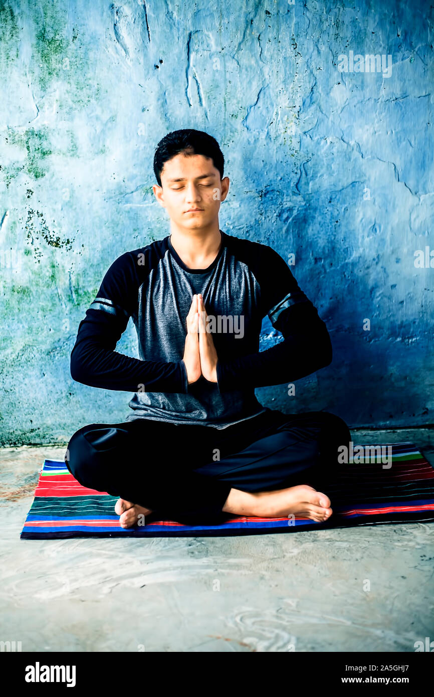 Einfache Pose oder sukhasana von einem jungen Mann auf der bunten Mat durch das Tragen schwarzer Kleidung durchgeführt. Stockfoto