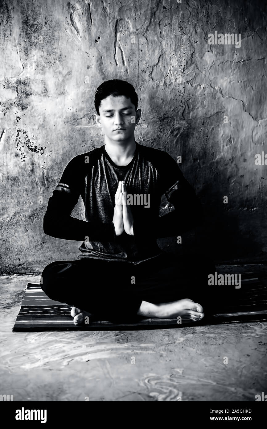Einfache Pose oder sukhasana von einem jungen Mann auf der bunten Mat durch das Tragen schwarzer Kleidung durchgeführt. Stockfoto