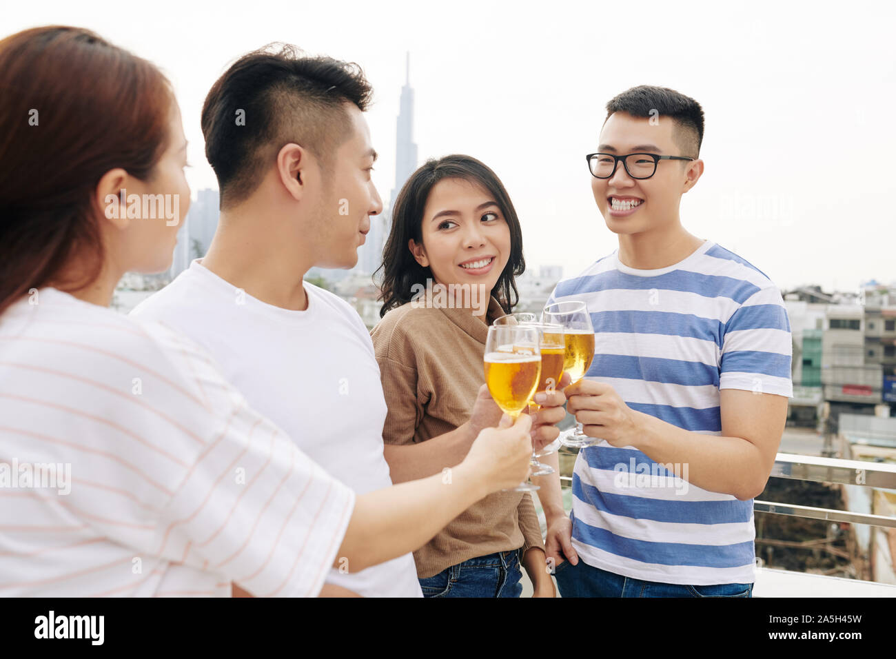 Vietnamesische IT-Unternehmen Arbeitnehmer schlichten Feiern erfolgreiches Projekt und trinken Champagner bei Gebäude auf dem Dach Stockfoto