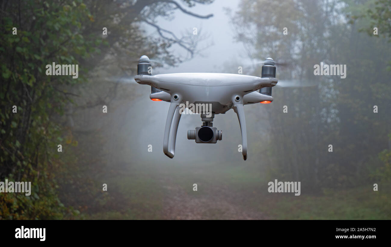 Eine Drohne schwebt im Flug auf einem Nebelhaften foggy autumn forest path. Stockfoto