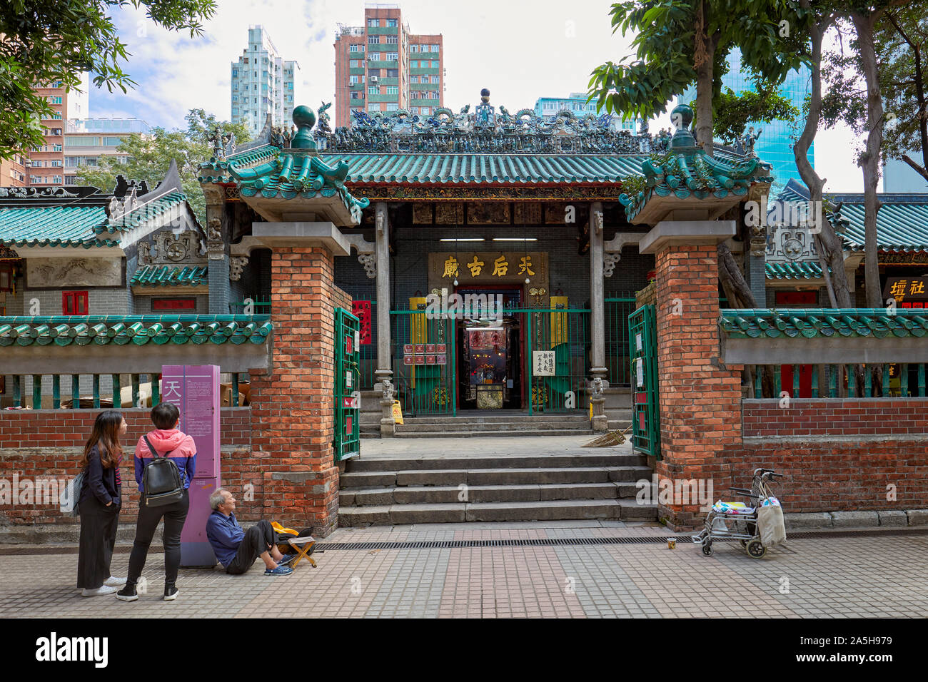 Touristen, die auf der Suche bei informationsstand am Eingang zu Tin Hau Tempel Komplex. Yau Ma Tei, Kowloon, Hong Kong. Stockfoto