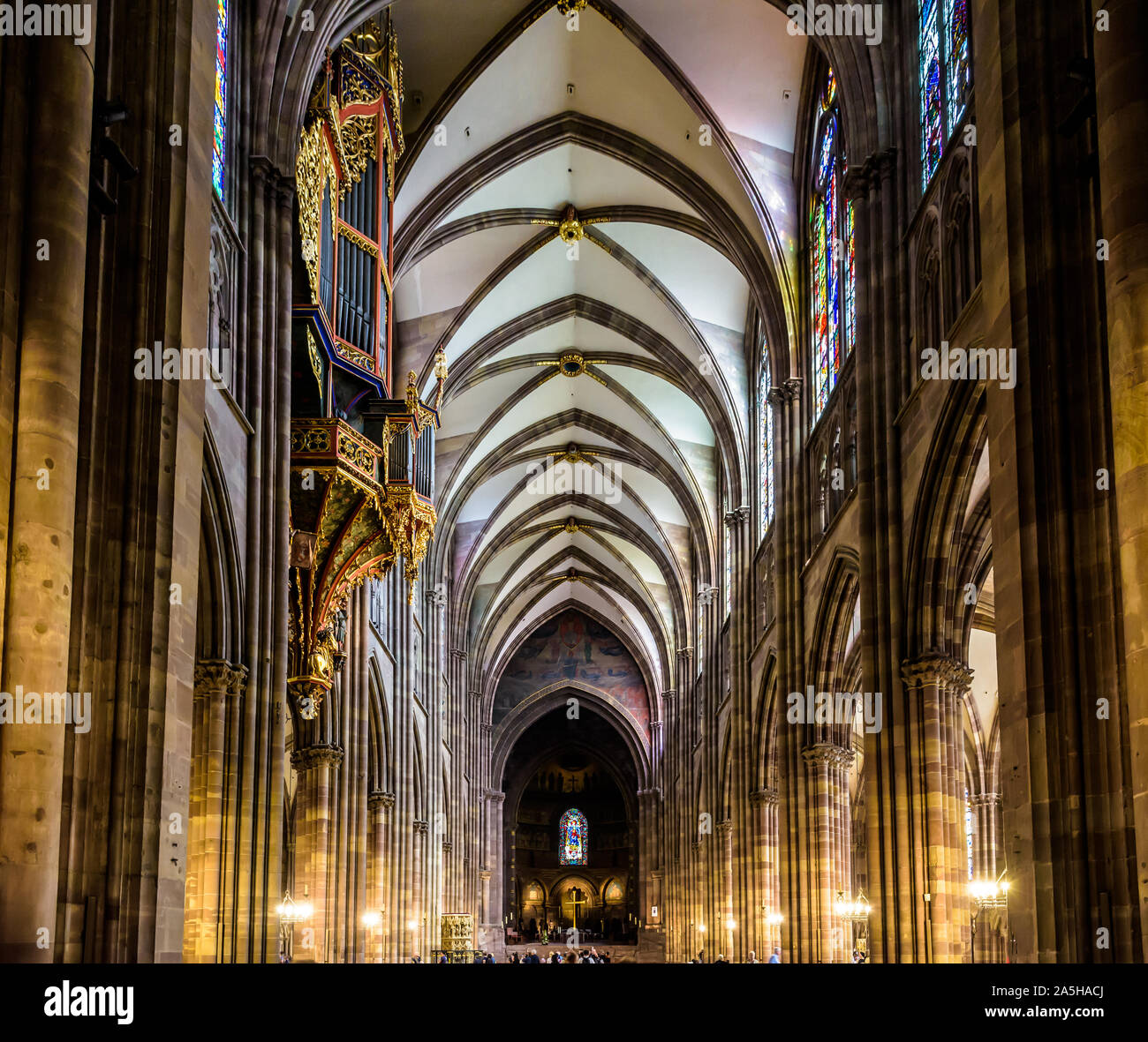 Das lange Kirchenschiff und Chor der Kathedrale Notre-Dame in Straßburg, Frankreich, beleuchtet durch Sonnenlicht mit der gefederten Orgel auf der linken Seite. Stockfoto