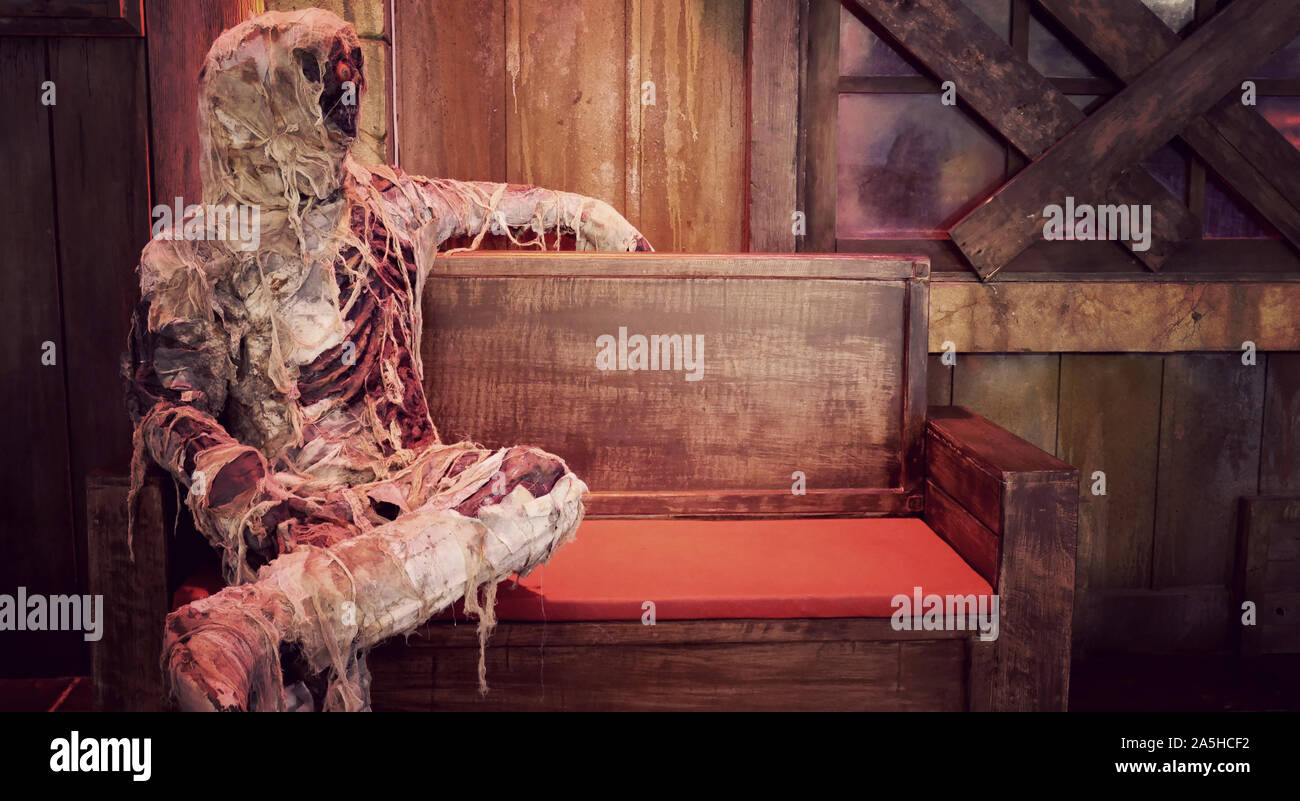 Mumie Modell des toten Mannes mit weißen Knochen in einem Tuch eingewickelt auf einer Bank mit Kopie Raum für Halloween Hintergrund sitzen Stockfoto