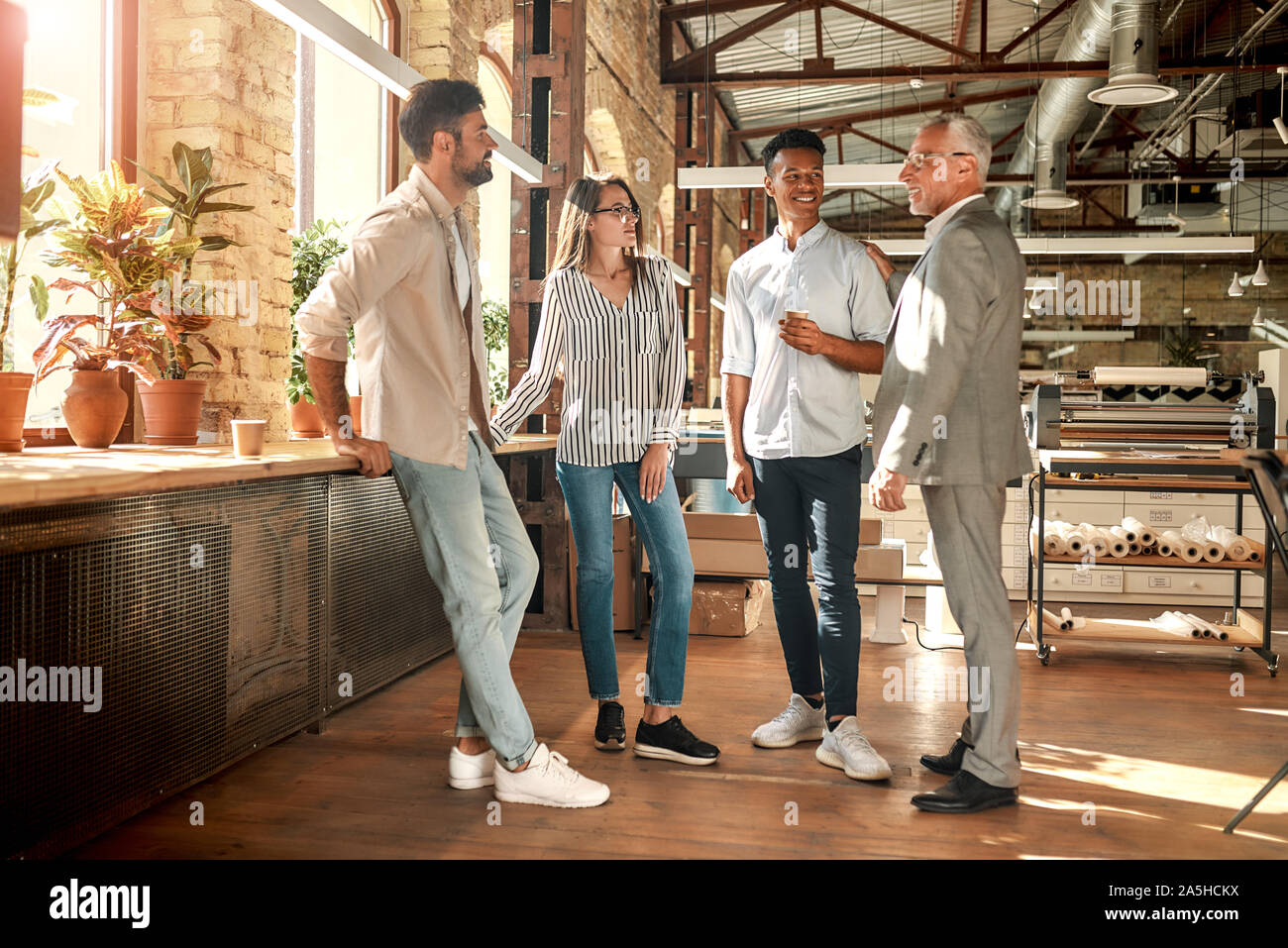 Gut gemacht! Fröhliche reifer Mann in formale Abnutzung tätschelte seine junge afro-amerikanischen Kollegen auf die Schulter beim Stehen mit Kollegen im modernen Büro Stockfoto