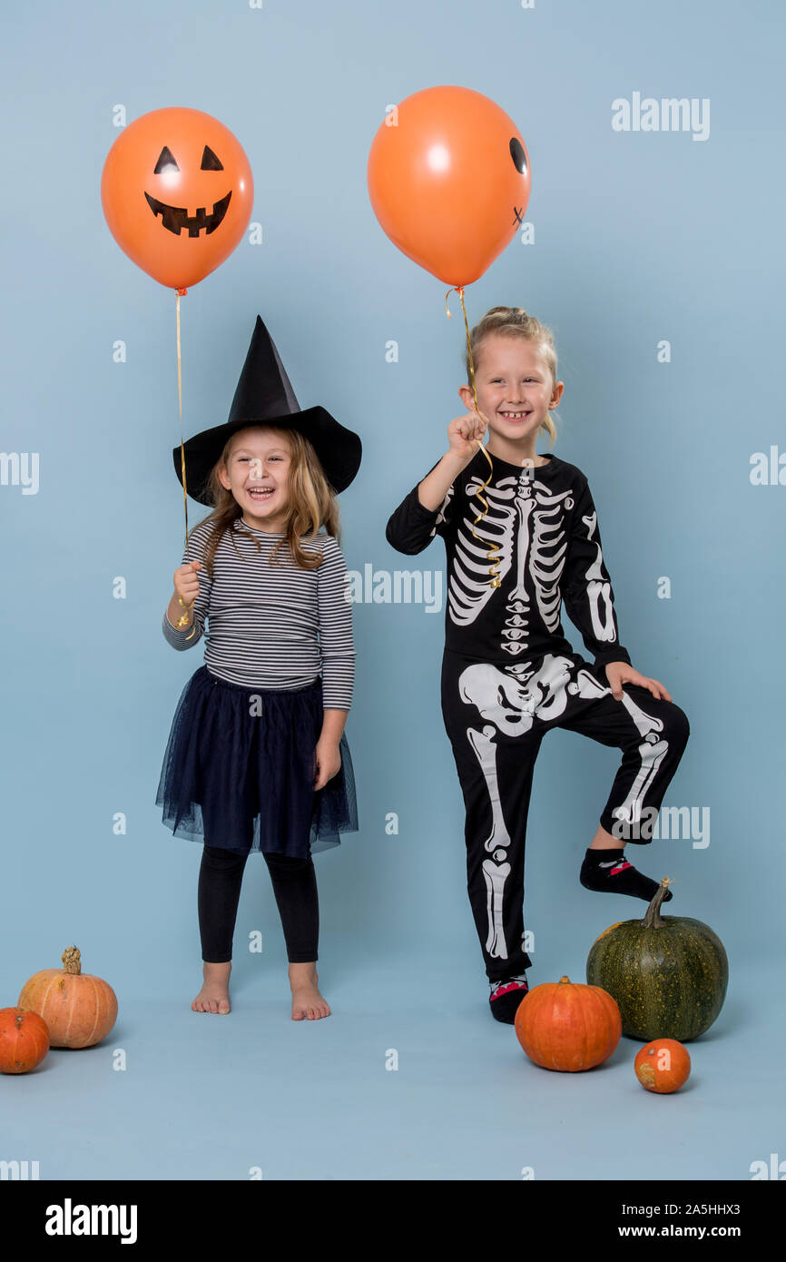 Zwei süße Kinder Hexe und Skelett Kostüme Holding orange halloween Ballons Stockfoto