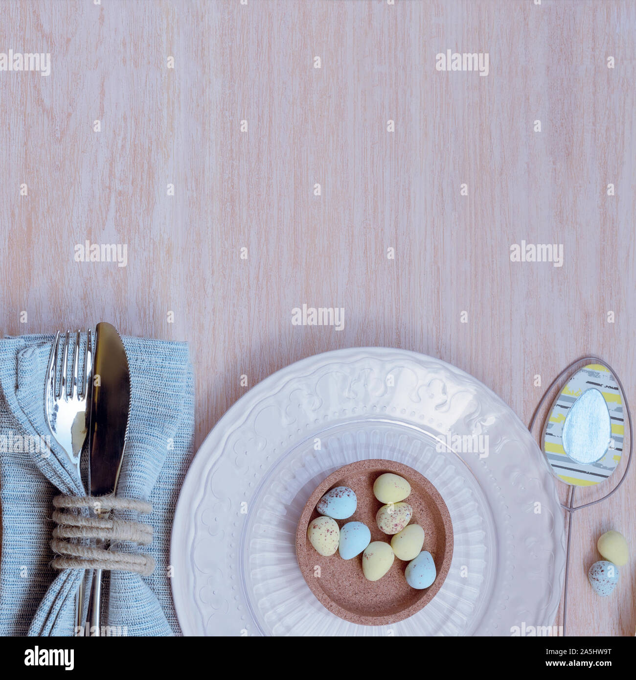 Frohe Ostern Konzept. Blick von oben auf die schöne Frühling Tabelle Einstellungen in Pastelltönen, blau Bettwäsche Serviette mit rustikalen Serviette ring und die Schüssel mit der Schokolade E Stockfoto