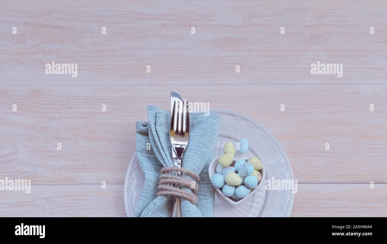 Frohe Ostern Konzept. Blick von oben auf die schöne Frühling Tabelle Einstellungen in Pastelltönen, blau Bettwäsche Serviette mit rustikalen Serviette ring und die Schüssel mit der Schokolade E Stockfoto