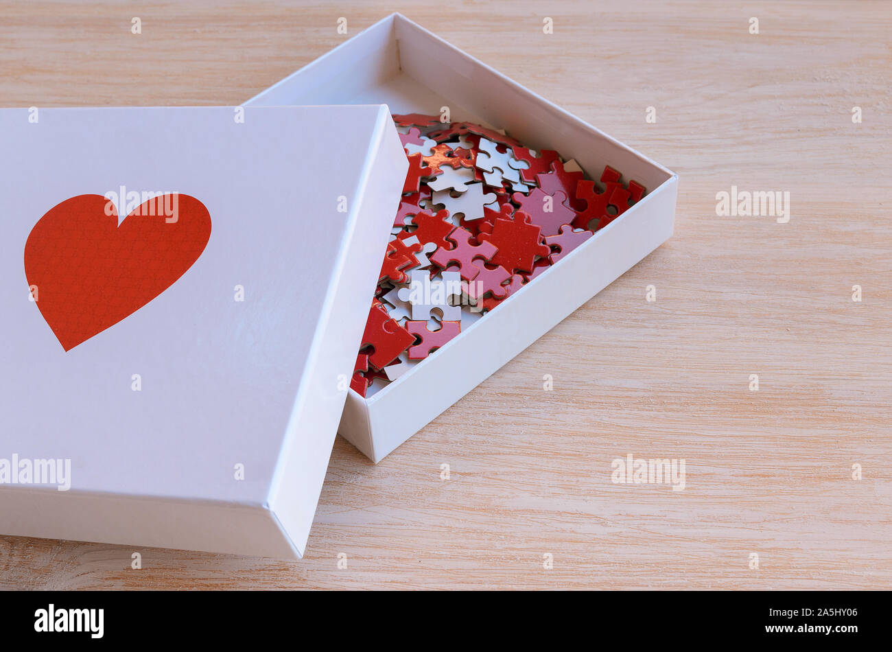 Box mit rotem Herz Puzzle auf weißem Holz- Hintergrund. Konzept für Liebe oder Nächstenliebe zu tun. Jedes Bisschen hilft Stockfoto