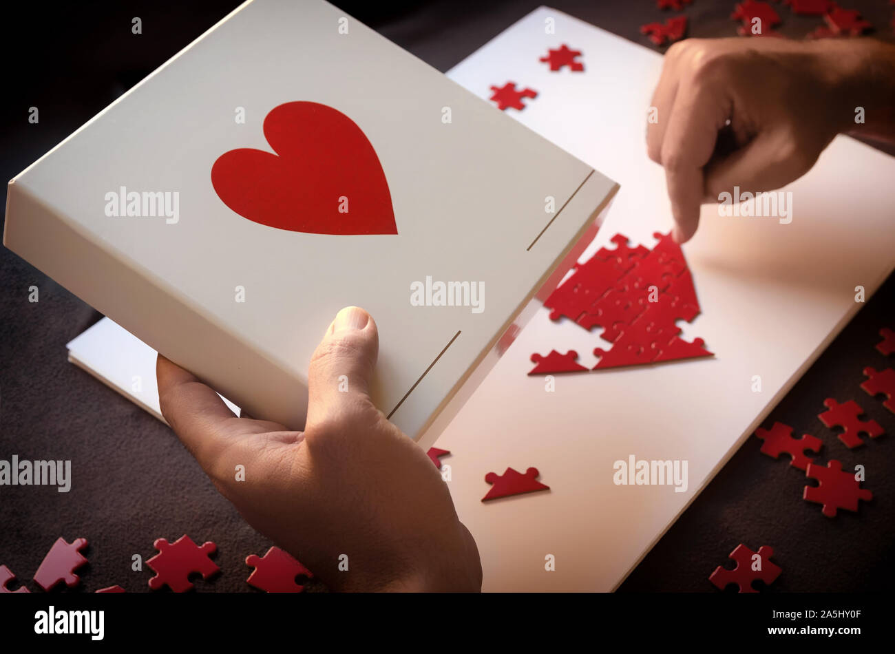 Mann, der rote herzförmige Puzzle. Konzept für Liebe oder Nächstenliebe zu tun. Jedes Bisschen hilft Stockfoto