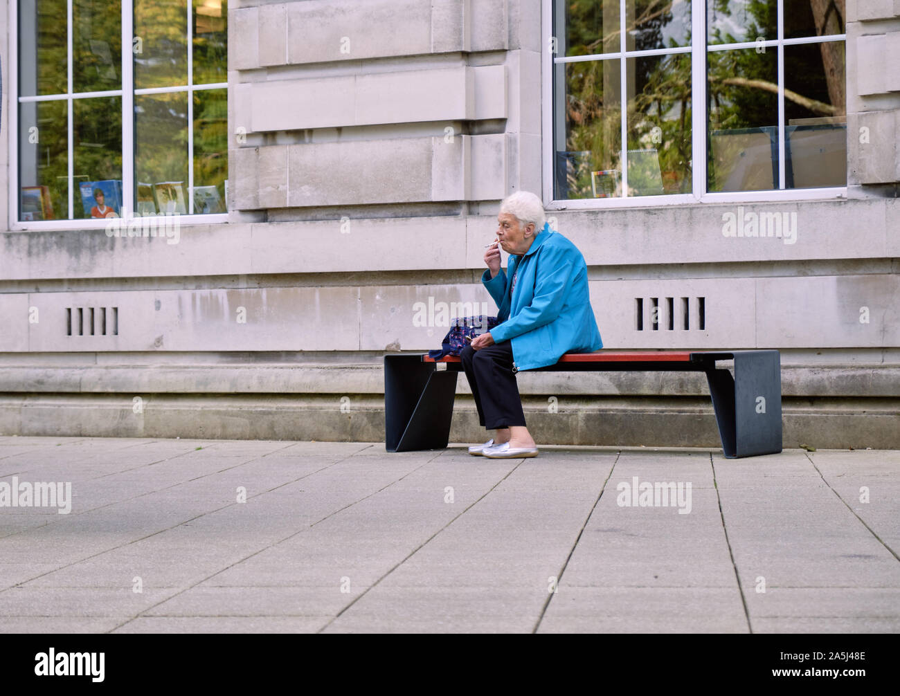 Ältere Dame eine Pause rauchen außerhalb vor dem Betreten des Belfast Nichtraucher Museum Stockfoto