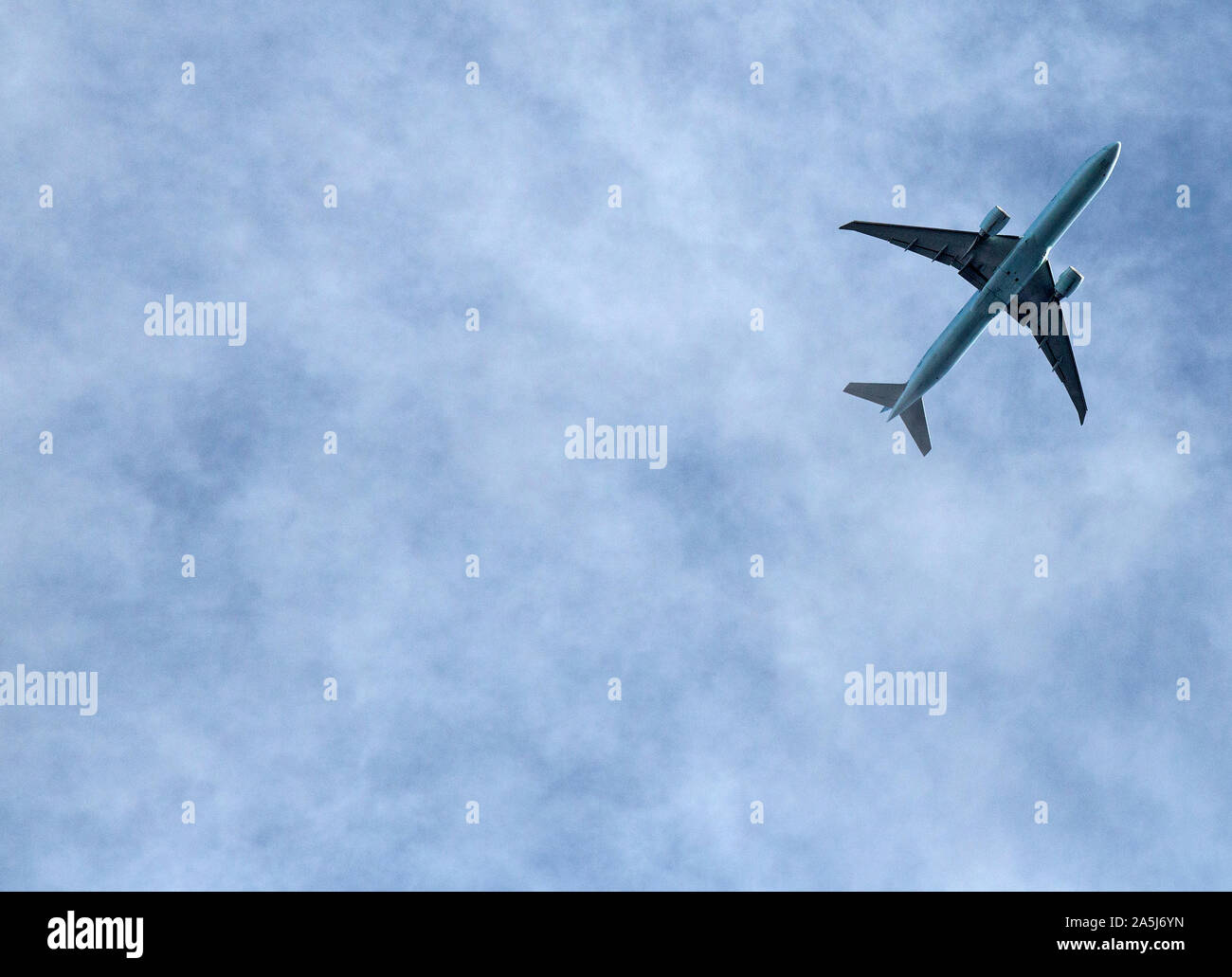 Ein Twin Jet Airliner gegen ein uneinheitliches blaue Wolke Himmel fliegen. Stockfoto