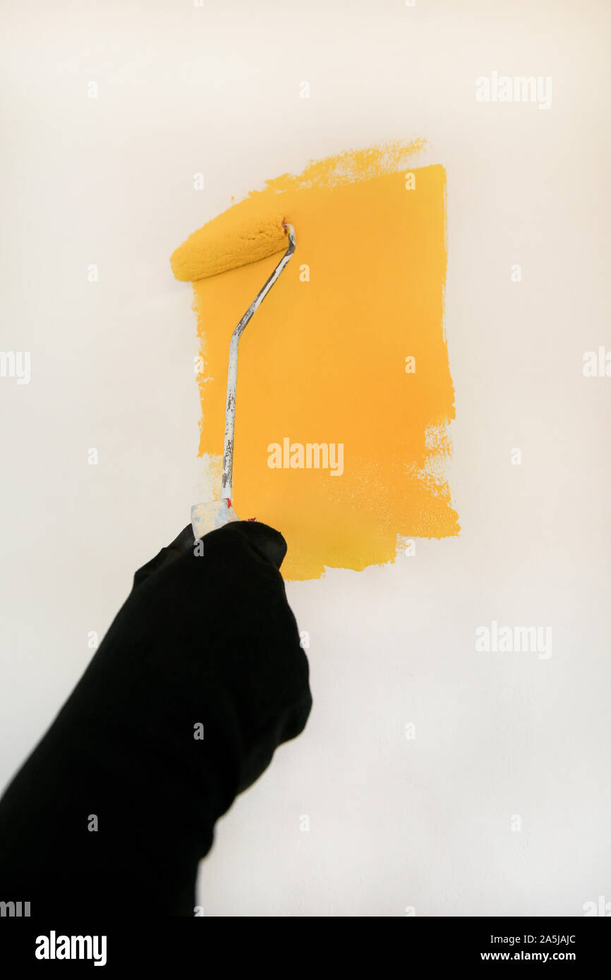 Bauarbeiter tun beenden Renovierung im Apartment. Professionelle Maler mit paint Bürstenrolle Anstrich der Wand mit der Farbe gelb. Stockfoto