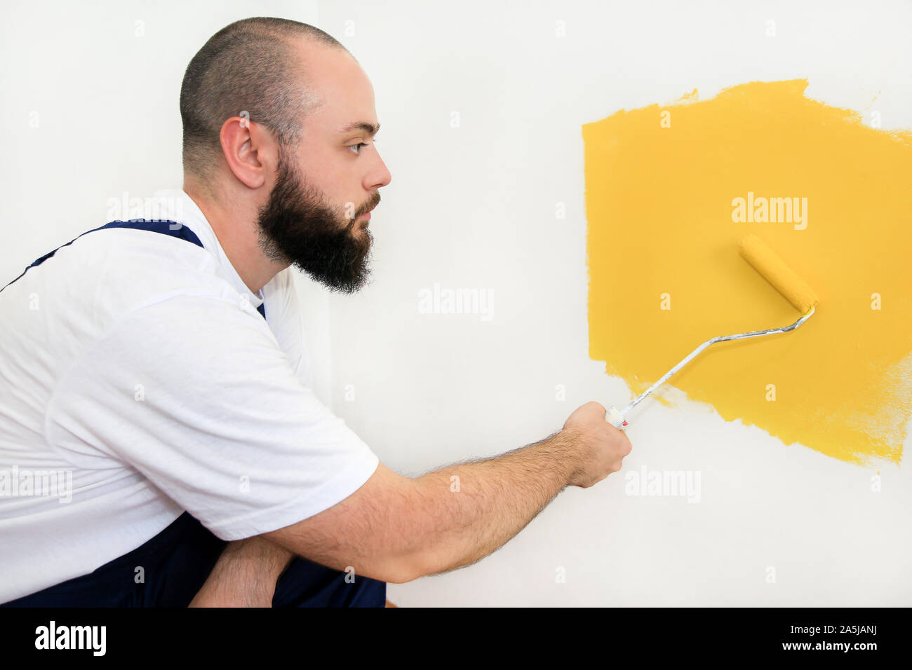 Bauarbeiter tun beenden Renovierung im Apartment. Professionelle Maler mit paint Bürstenrolle Anstrich der Wand mit der Farbe gelb. Stockfoto
