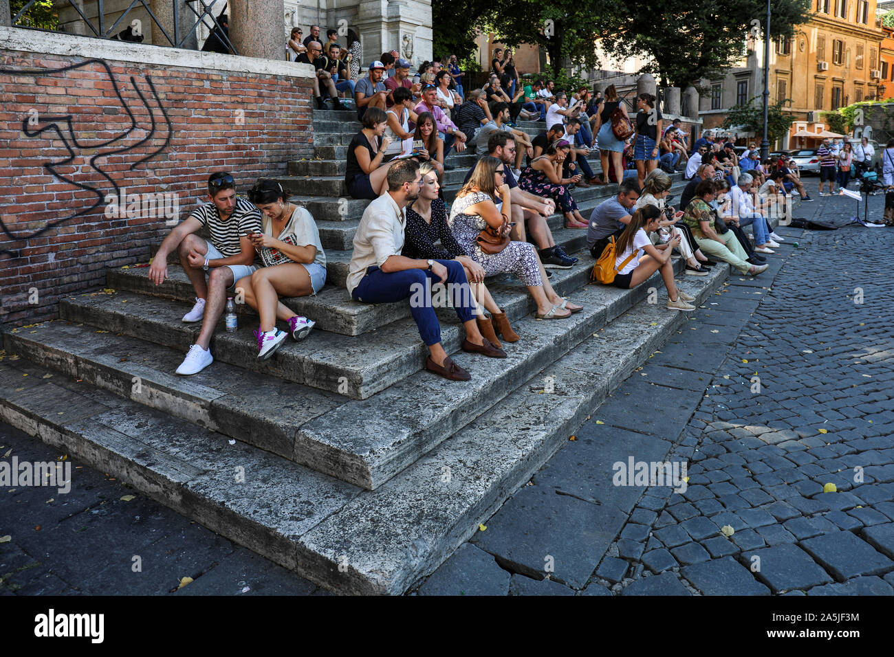 Einheimische und Touristen hören zu einem Gaukler auf die Schritte der Fontana di Ponte Sisto in Trastevere in Rom, Italien Stockfoto
