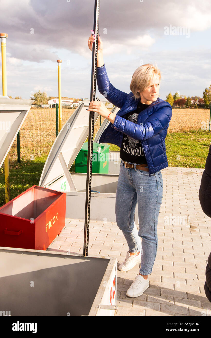 Eine junge Frau, Einzelhandel Tankstelle Direktor in der Ukraine Maßnahmen Diesel mit Eichung ritt als Ingenieure elektronische Vermessung rodes bei Gas Station installieren Stockfoto