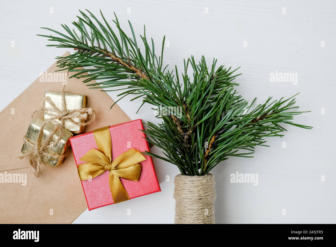 Rote und goldene Geschenke, Handwerk Umschlag, natürlichen grünen Pinien Zweige, Flaschenhals auf weißem Hintergrund mit Garn umwickelt. Stockfoto