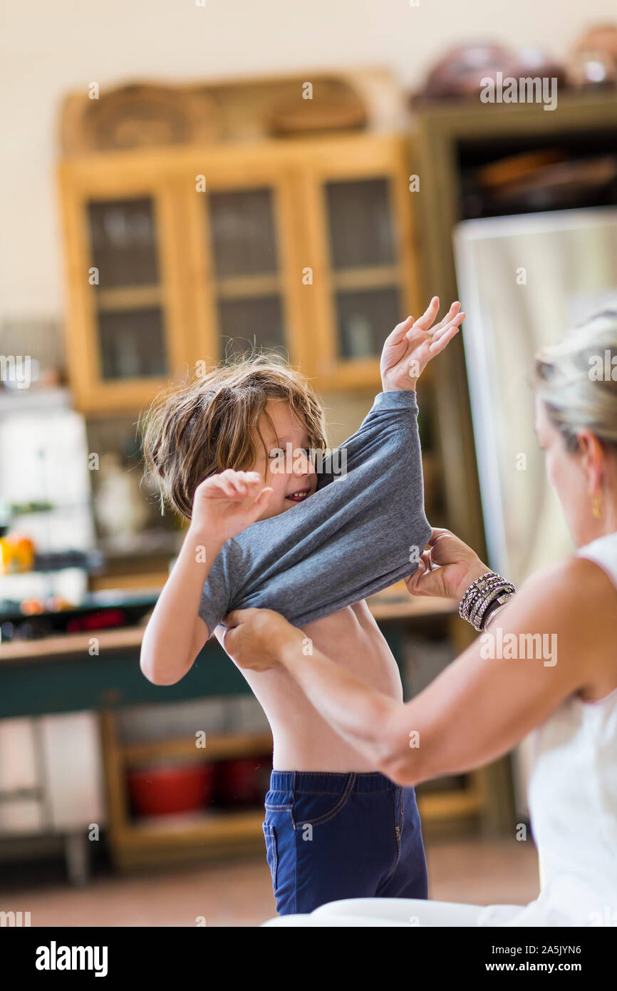 Mutter helfen Ihr 5 Jahre alter Junge angekleidet zu erhalten Stockfoto