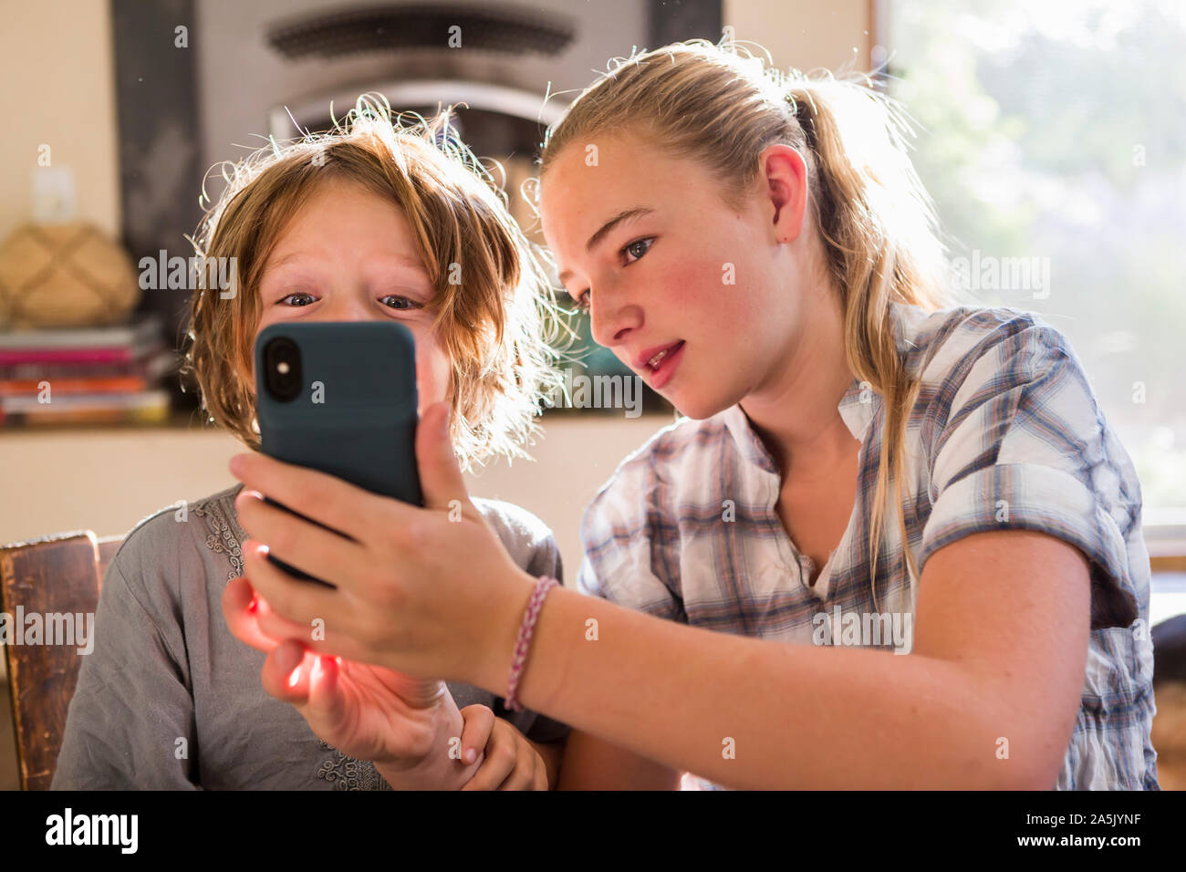 Zwei Kinder, Teenager und ihr 6-jähriger Bruder Holding ein smart phone, selfies nehmen. Stockfoto