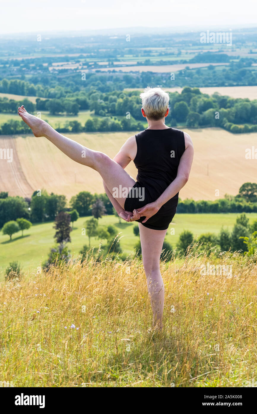 Reife Frau, die an einer Yogastunde auf einem Hügel. Stockfoto