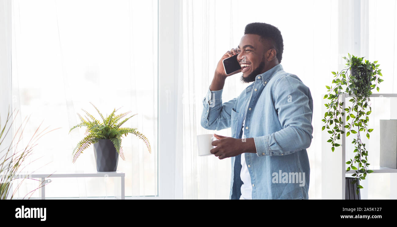 Junge fröhliche Geschäftsmann am Telefon sprechen und halten Kaffee Tasse Stockfoto