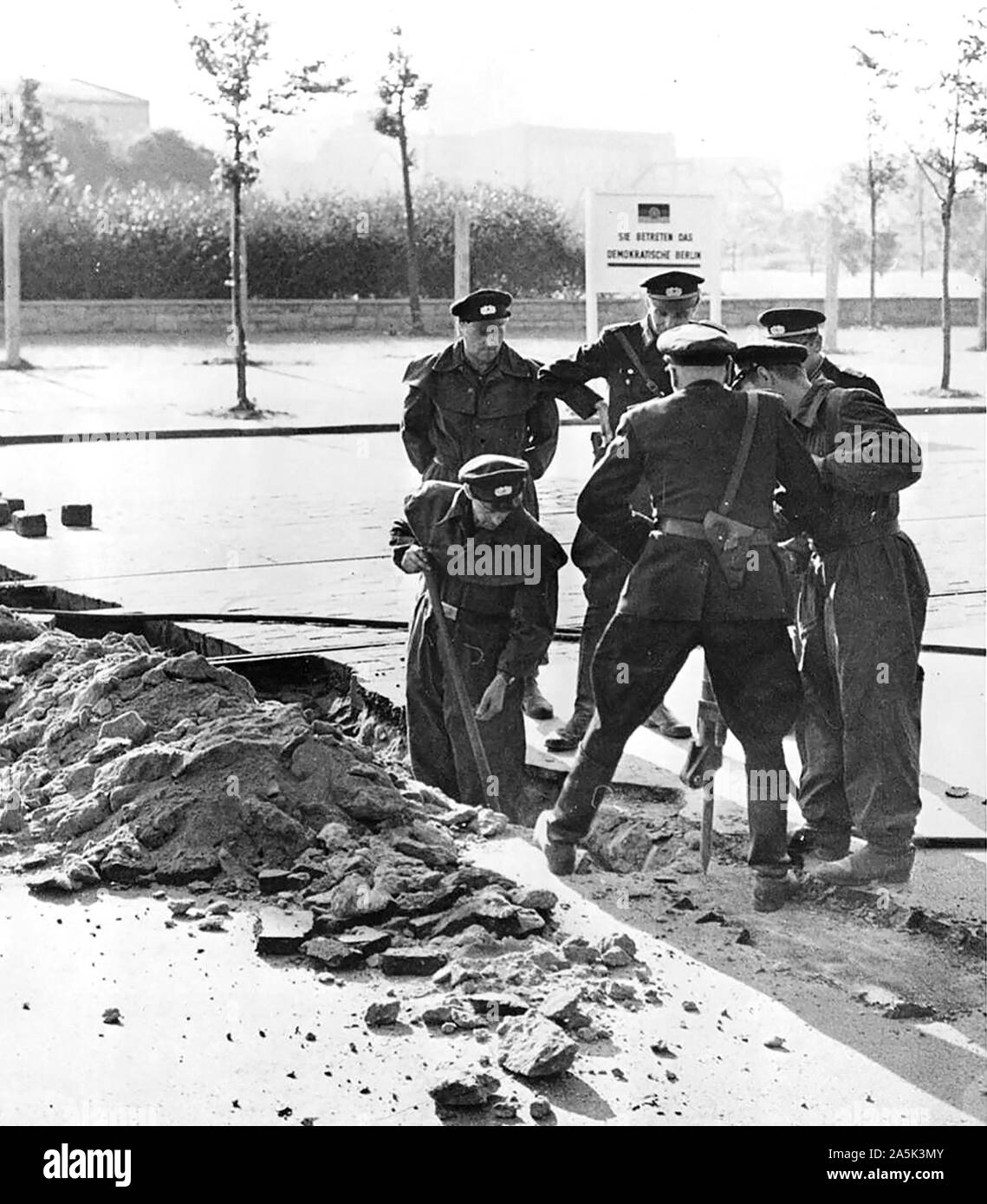 Datum - Möglicherweise im August 1961 - Polizei reißen die Fahrbahn in der Nähe von Potsdamer Platz zu bauen dauerhafte Straße blockieren. Kommunistische errichtet Schild im Hintergrund liest: "Sie betreten demokratischen Berlin." Stockfoto
